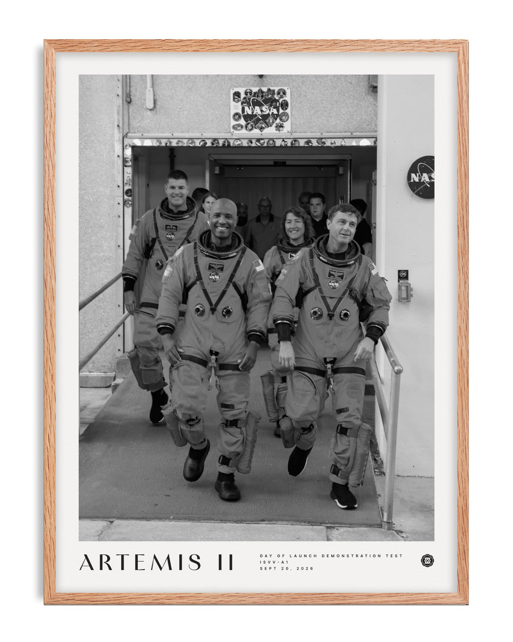 Oak-framed Artemis II crew art print featuring four astronauts in spacesuits walking out of a NASA building.