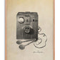 Oak-framed art print illustrating a 1947 external defibrillator with a wooden control box and wired paddles.