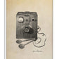 White-framed art print illustrating a 1947 external defibrillator with a wooden control box and wired paddles.