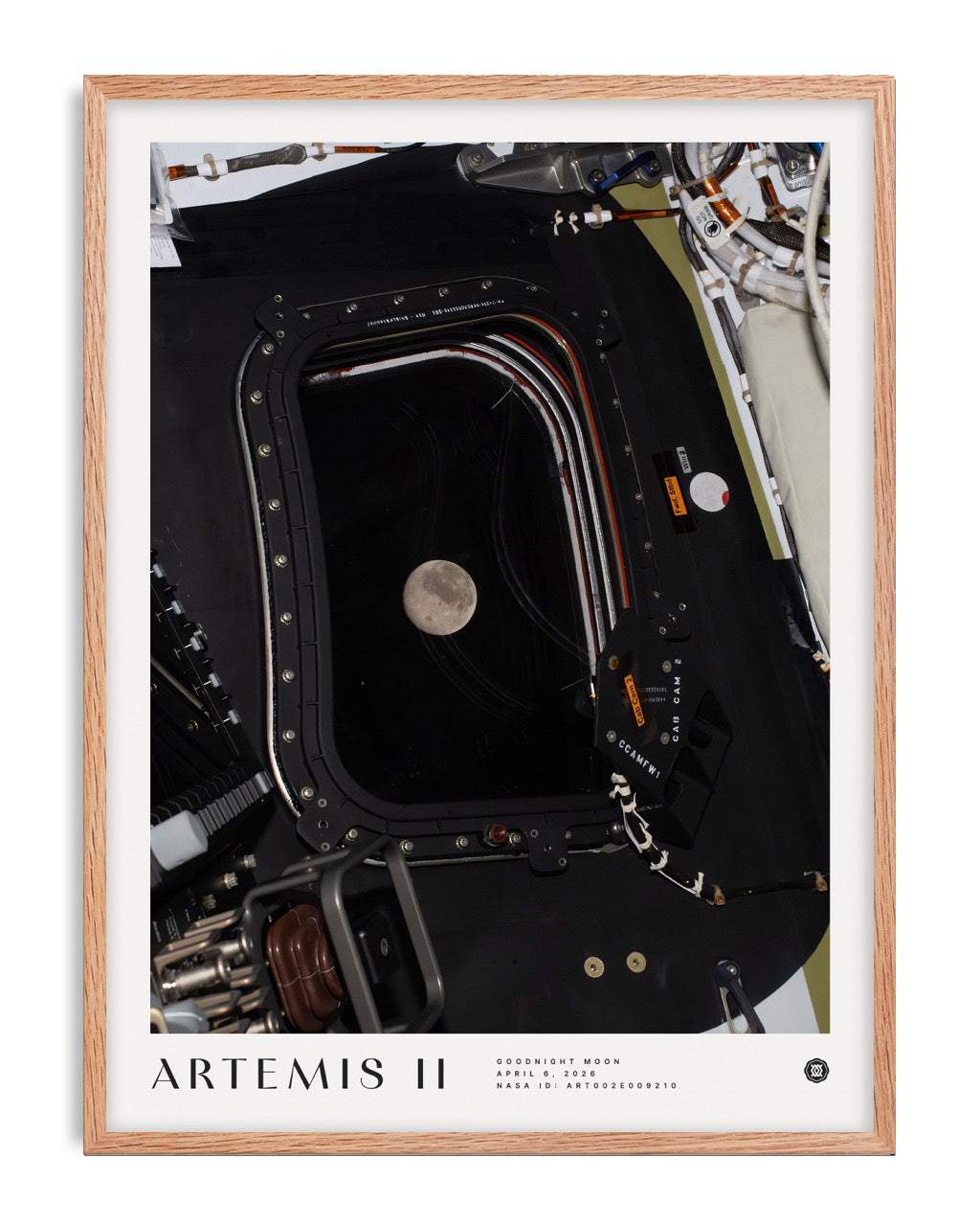 Oak-framed Artemis II Goodnight Moon art print showing the Moon through a spacecraft window surrounded by equipment.