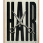 Oak-framed HAIR artwork with oversized black lettering and open silver haircutting scissors.