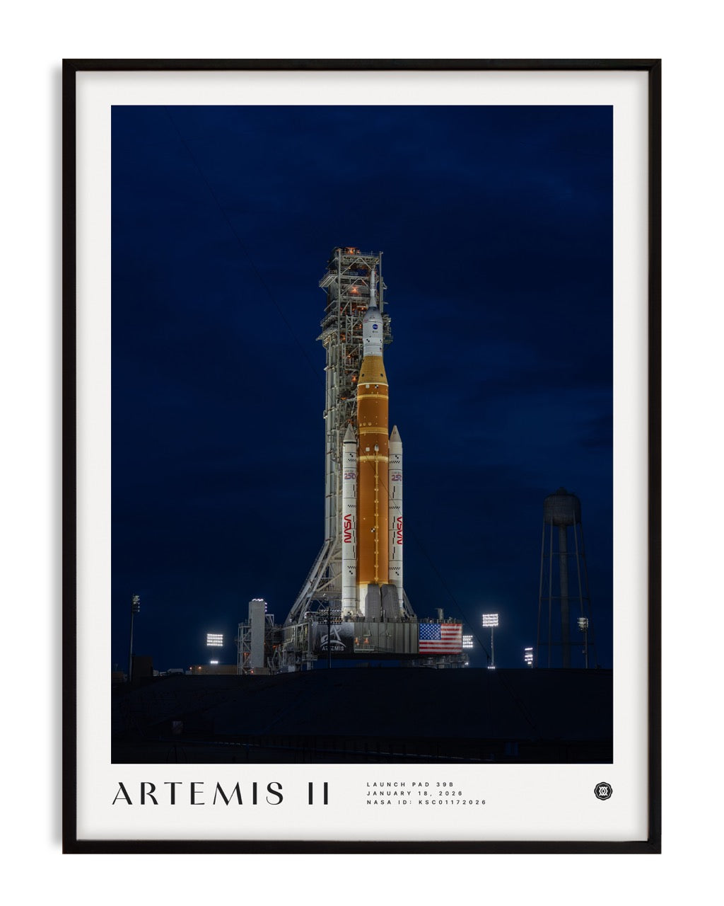 Black-framed Artemis II art print showing a NASA rocket illuminated on a launch pad at night.