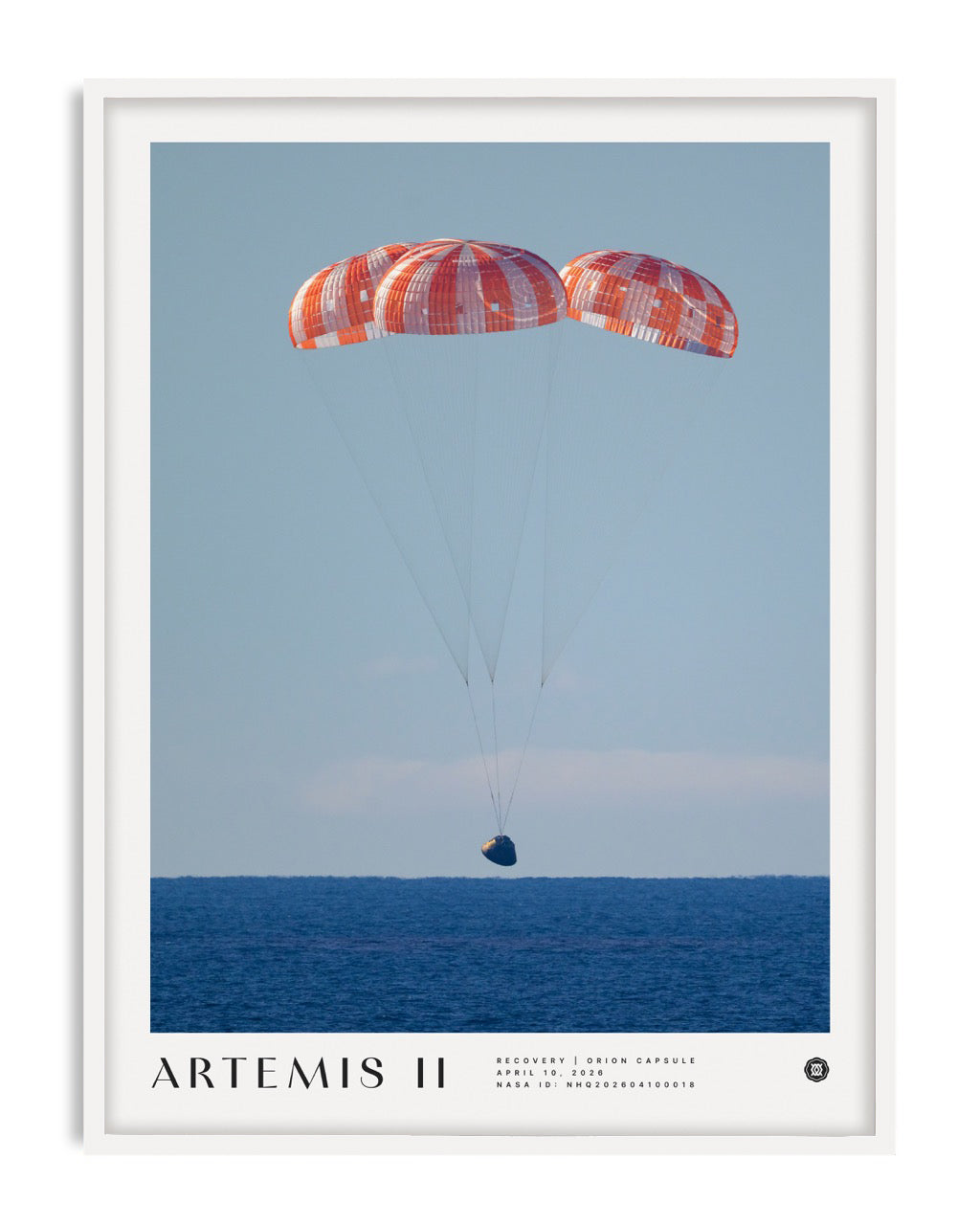 White-framed Artemis II art print showing the Orion capsule descending beneath three parachutes over the ocean.