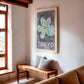 Oak-framed Tokyo 1982 Festival of the Cherry Blossoms artwork hanging above a wooden bench in a sunlit living room.
