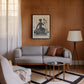 Black-framed Lady Justice artwork displayed in a living room above a gray sofa against a wood-paneled wall.