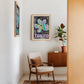 Oak-framed Tokyo 1982 Festival of the Cherry Blossoms artwork hanging above a chair beside a cabinet and potted plant.