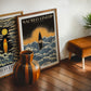 Oak-framed Sacred Lineup Oahu Hawaii artwork displayed on a wooden floor with another art print, a striped vase, and a chair.