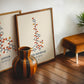 Oak-framed beta-endorphin molecular artwork leaning beside an oxytocin print and striped wooden vase.