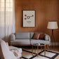 Black-framed dopamine molecular artwork displayed above a gray sofa on a wood-paneled living room wall.