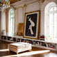 Ornately framed Blowout art print displayed above bookshelves in a living room.