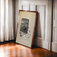 Dark wood-framed vintage external defibrillator artwork leaning against paneled walls beside a sunlit window.