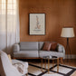Black-framed beta-endorphin molecular artwork displayed above a gray sofa on a wood-paneled living room wall.
