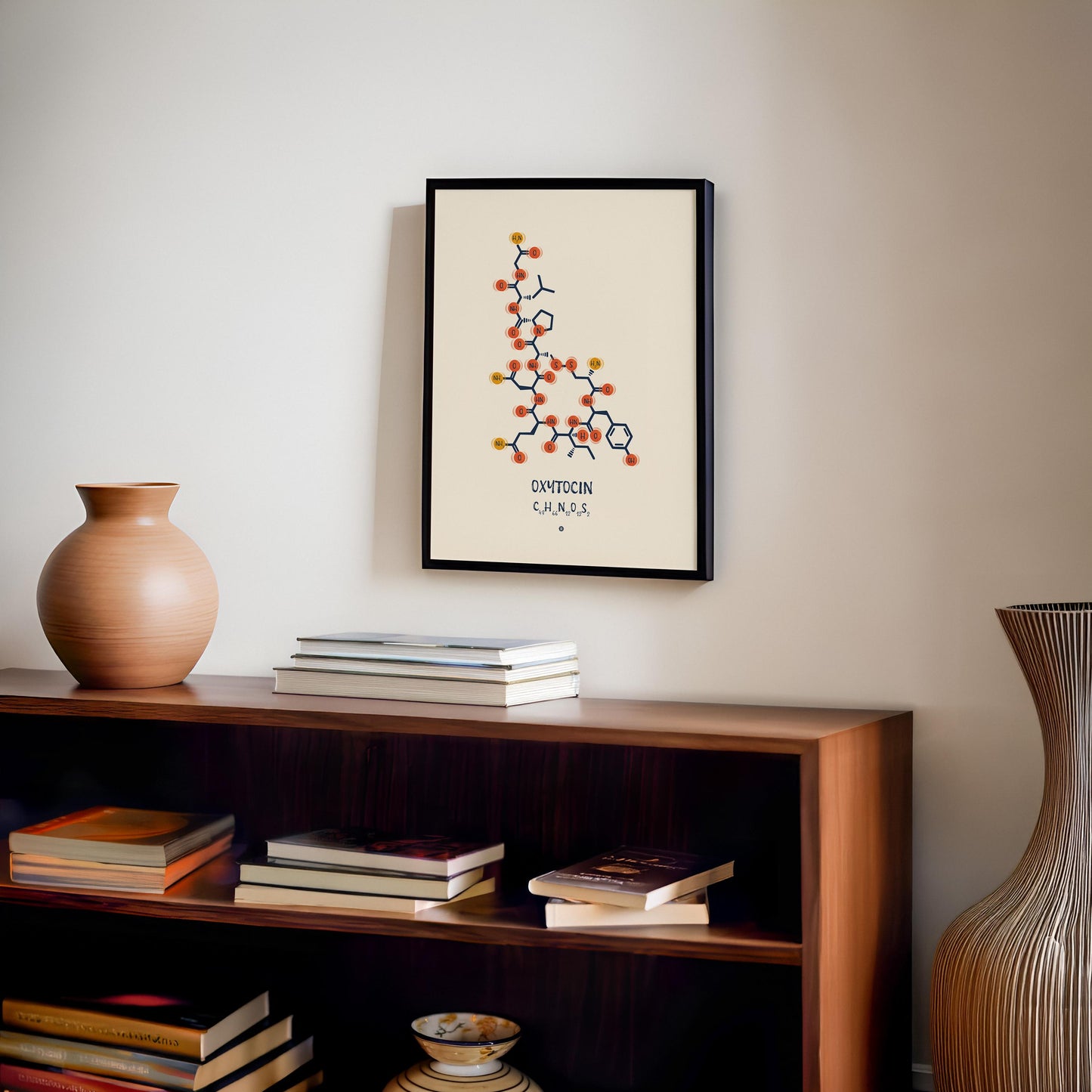 Black-framed oxytocin molecular artwork displayed above a wooden bookcase with books and a ceramic vase.