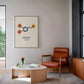 Black-framed dopamine molecular artwork displayed above a rust-colored armchair in a modern living room.