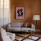 Black-framed Chōwa koi fish artwork displayed above a gray sofa on a wood-paneled living room wall.