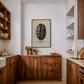Framed Hawaii Kona coffee bean art print displayed above wooden cabinets in a kitchen.