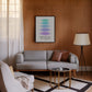 Black-framed Hierarchy of Needs art print displayed above a gray sofa in a living room.