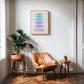 Oak-framed Hierarchy of Needs art print displayed above a tan leather chair and potted plants.