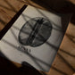 Unframed Kenya coffee bean art print lying on a wooden floor beneath leafy shadows