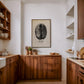 Framed Kenya coffee bean artwork displayed above wooden cabinets in a bright kitchen