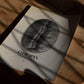 Unframed Ethiopia Yirgacheffe, Sidamo coffee bean art print lying on a wooden table beneath window shadows.
