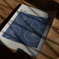 Unframed RIDE. art print with white bicycle line drawings on blue lying on a sunlit wooden table.