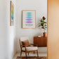 Oak-framed Hierarchy of Needs art print displayed above an armchair beside a potted plant.