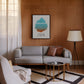 Black-framed Anger Iceberg art print displayed above a gray sofa in a wood-paneled living room.