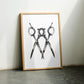 Oak-framed monochrome scissors artwork leaning against a wall between two chairs.