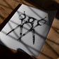 Monochrome art print of three overlapping scissors lying on a wooden floor in window shadows.