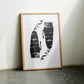 Oak-framed abstract black-and-white artwork leaning against a wall between two chairs.