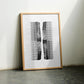 Oak-framed abstract comb artwork leaning against a wall between two chairs.