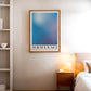 Oak-framed Silent Reflection No.1 blue and lavender gradient art print hanging above a bedside table in a bedroom.