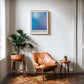 Oak-framed Silent Reflection No.1 blue and lavender gradient art print above a leather chair and potted plants in a living room.