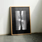 Oak-framed white abstract comb artwork leaning between two chairs.