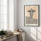 Black-framed Caduceus art print displayed above a sunlit window seat with cushions, books, and flowers.