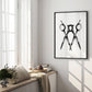 Black-framed monochrome scissors artwork displayed on a sunlit wall above a window seat.