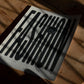 Unframed FASHION typography art print with button and looping thread on a sunlit wooden table.