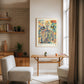 Oak-framed Corporis in Bloom artwork displayed above a narrow wooden table in a bright reading area.