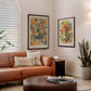 Two Black-framed floral anatomy art prints displayed above a tan leather sofa in a living room.