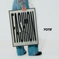 Person in jeans holding a Black-framed FASHION typography artwork beside the YOTIF name.
