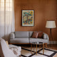 Black-framed Hepar in Bloom artwork displayed above a gray sofa on a wood-paneled living room wall.