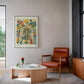Framed floral anatomy artwork displayed above a rust-colored armchair in a modern living room.