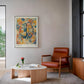Black-framed Cerebrum in Bloom art print displayed above a rust-colored armchair in a living room.