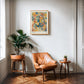 Oak-framed Cerebrum in Bloom art print displayed above a tan leather chair and potted plant.