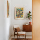 Oak-framed Hepar in Bloom artwork displayed above a chair and cabinet with a potted plant.
