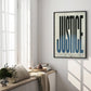 Black-framed JUSTICE typography artwork displayed on a sunlit wall beside tall windows
