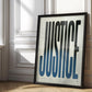 Black-framed JUSTICE typography artwork leaning against a sunlit paneled wall