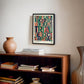 Black-framed colorful legal-themed artwork hanging above a wooden bookcase with books and a ceramic vase.
