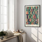 Black-framed colorful legal-themed artwork hanging in a sunlit room above a cushioned window bench and flowers.